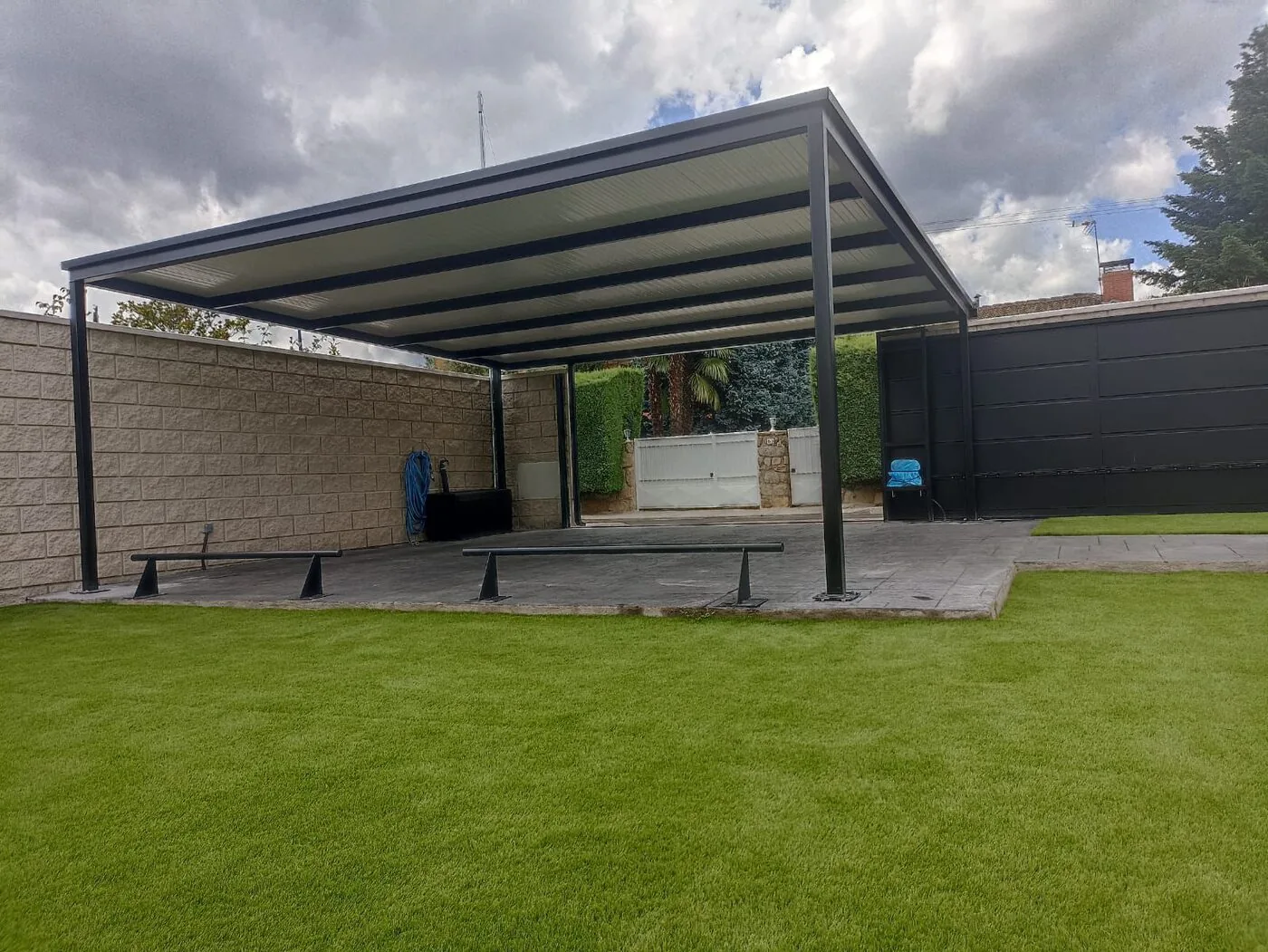 Pérgola plana de acero negro instalada en jardín particular en Madrid