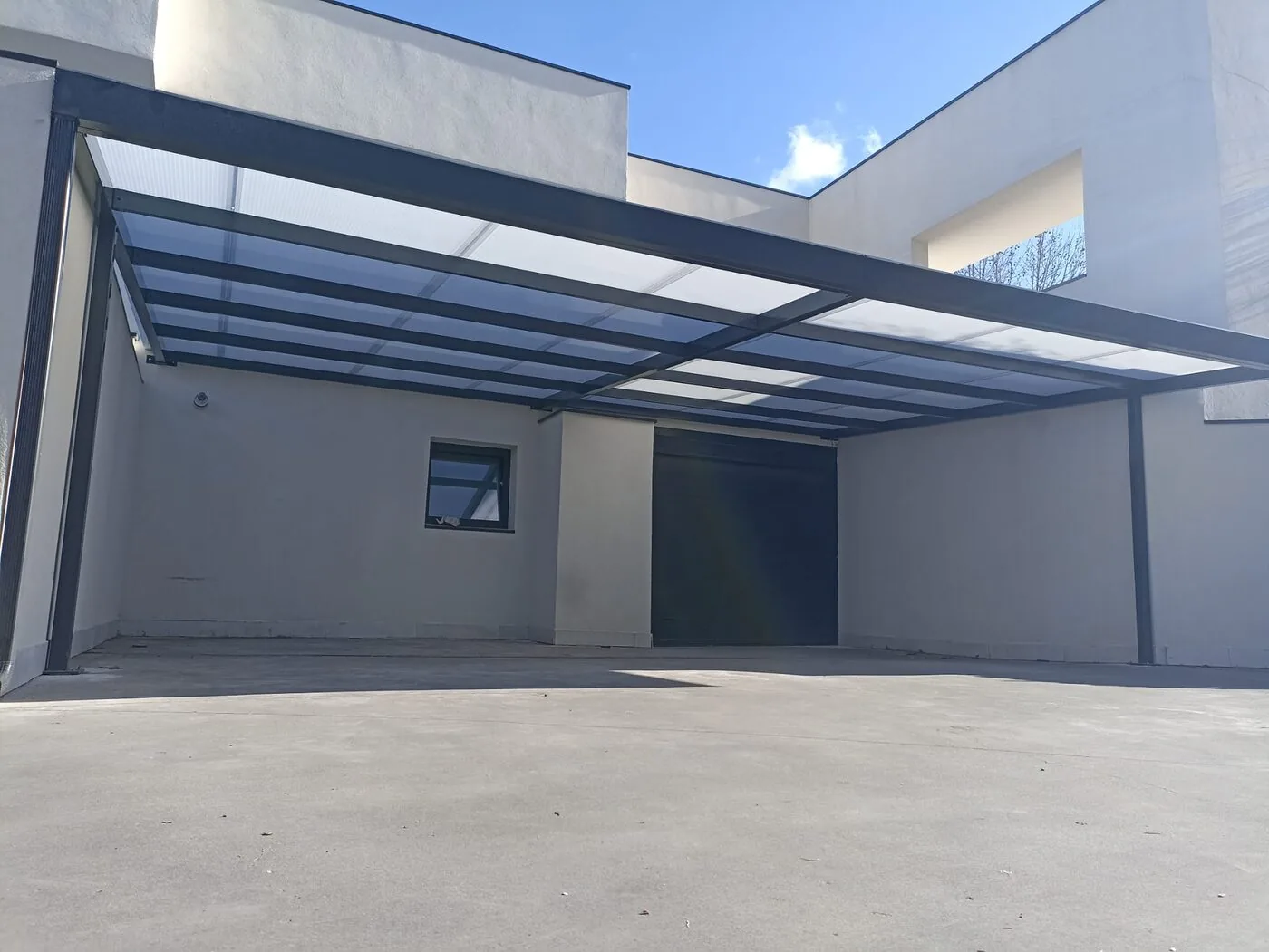 Carport adosado a vivienda con paredes blancas