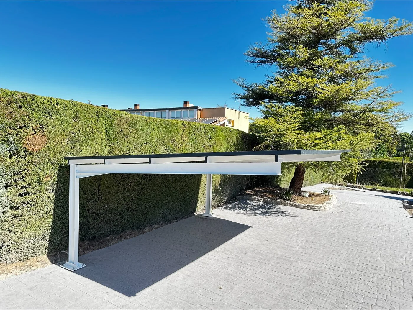 Carport con cubierta voladiza ligera junto a seto
