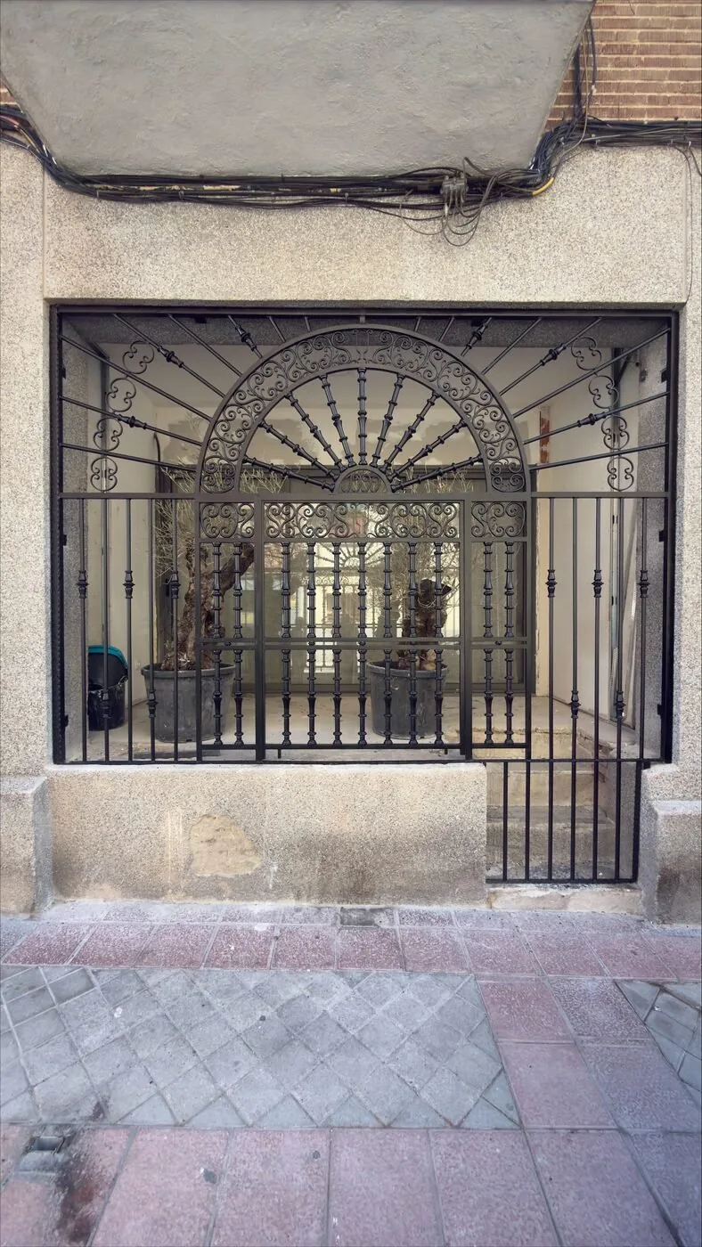 Reja de arco forjada instalada y lacada en negro en una fachada de la Comunidad de Madrid