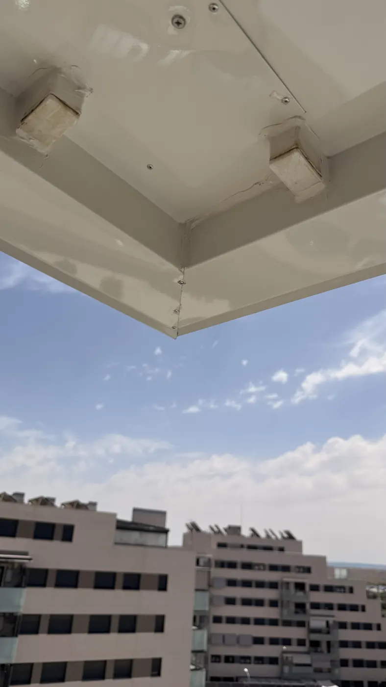 Marquesina metálica lacada en blanco instalada en la terraza de un ático de Madrid, con el montaje realizado en altura con arnés de seguridad